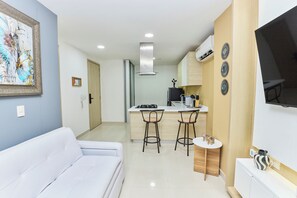 Eine moderne Küche mit einer zentralen Kochinsel, Barhocker und einem an der Wand montierten Flachbildfernseher.