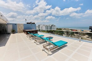 A rooftop terrace with lounge chairs and a pool table, overlooking a beach and residential buildings. - Apartment in Cartagena, in a tourist area, near the beach and the airport (La Boquilla)