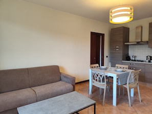 Ein modernes Wohnzimmer mit einer Couch, einem Esstisch mit Stühlen und einer Küchenzeile mit Schränken und einem Herd.