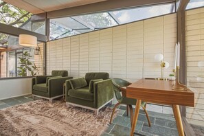 A modern interior with a glass ceiling, green upholstered chairs, a wooden desk, and a fluffy rug. - Spacious 4 BR GULF Front POOL Home! Private Dock with Boat Lift! FREE Golf Cart! (Palm Harbor)