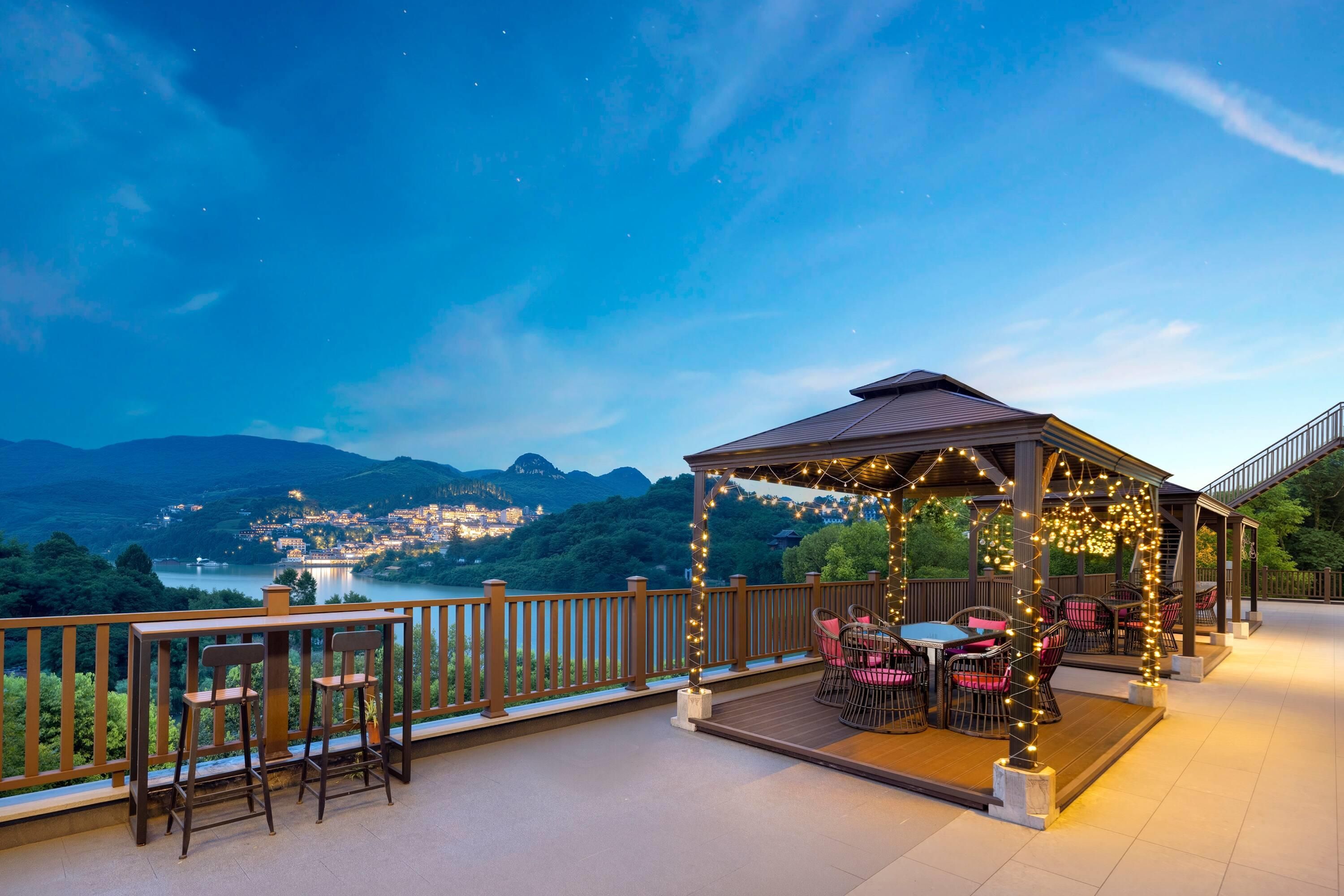 Un gazebo con luci a tendina, posti a sedere all'aperto e vista su una città e montagne.