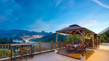 Un gazebo con luci a tendina, posti a sedere all'aperto e vista su una città e montagne.