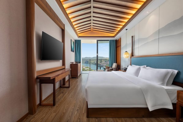 A hotel room with a large bed, a flat-screen TV, a wooden bench, a desk, and a view of the outdoors. - Wingate By Wyndham Xiangxi Furong Town (Xiangxi)