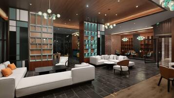 A modern lobby with a sectional sofa, armchairs, a coffee table, and a bookshelf.