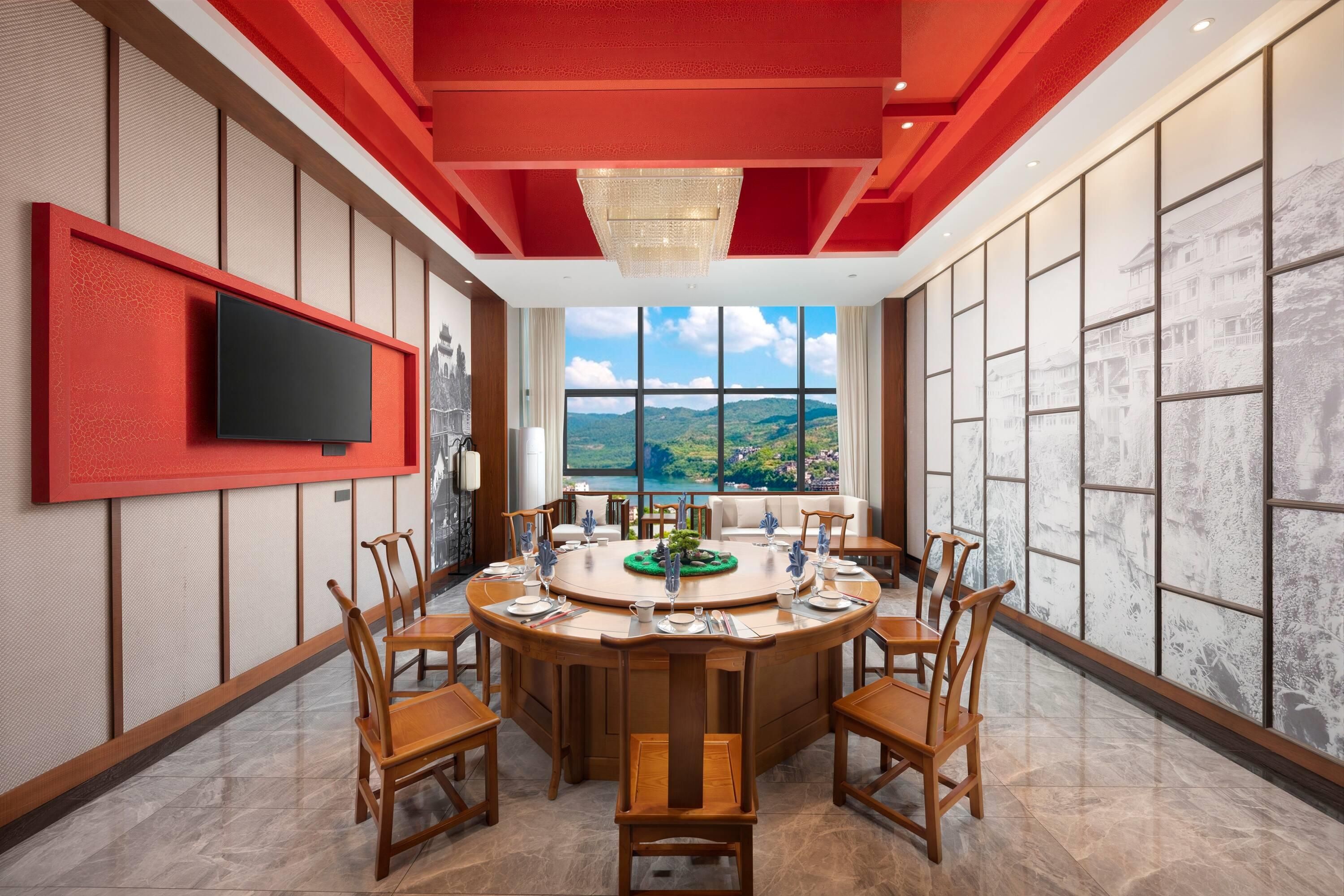 A dining area with a round table, chairs, and a television mounted on the wall.