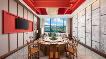 A dining area with a round table, chairs, and a television mounted on the wall.