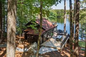A cabin with a deck overlooking a lake, surrounded by trees. - Darling 4 bed 2 bath cottage on Lake Muskoka, minutes from Bala (Parry Sound Mid-Shore (Bala))