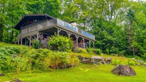 Een chalet met terras, omringd door weelderige begroeiing en bomen.