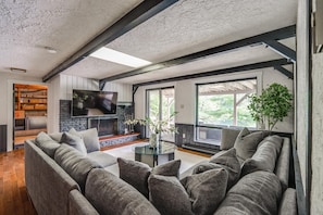 Ein modernes Wohnzimmer mit Kamin, Fernseher und einem großen Fenster.