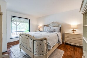 Een slaapkamer met een bed, nachtkastjes, een raam en een deur.