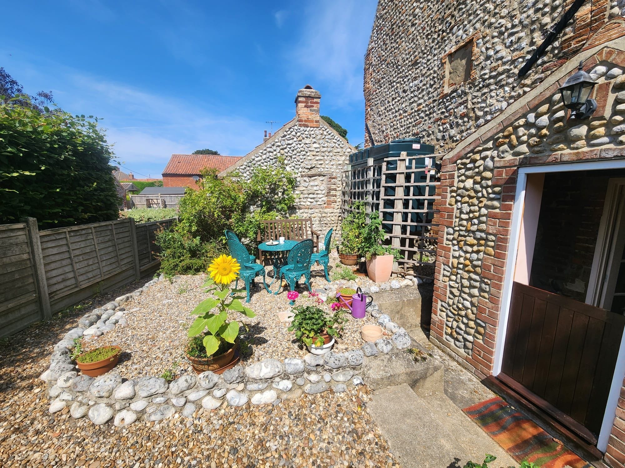 A courtyard with a stone wall, a wooden bench, and potted plants.