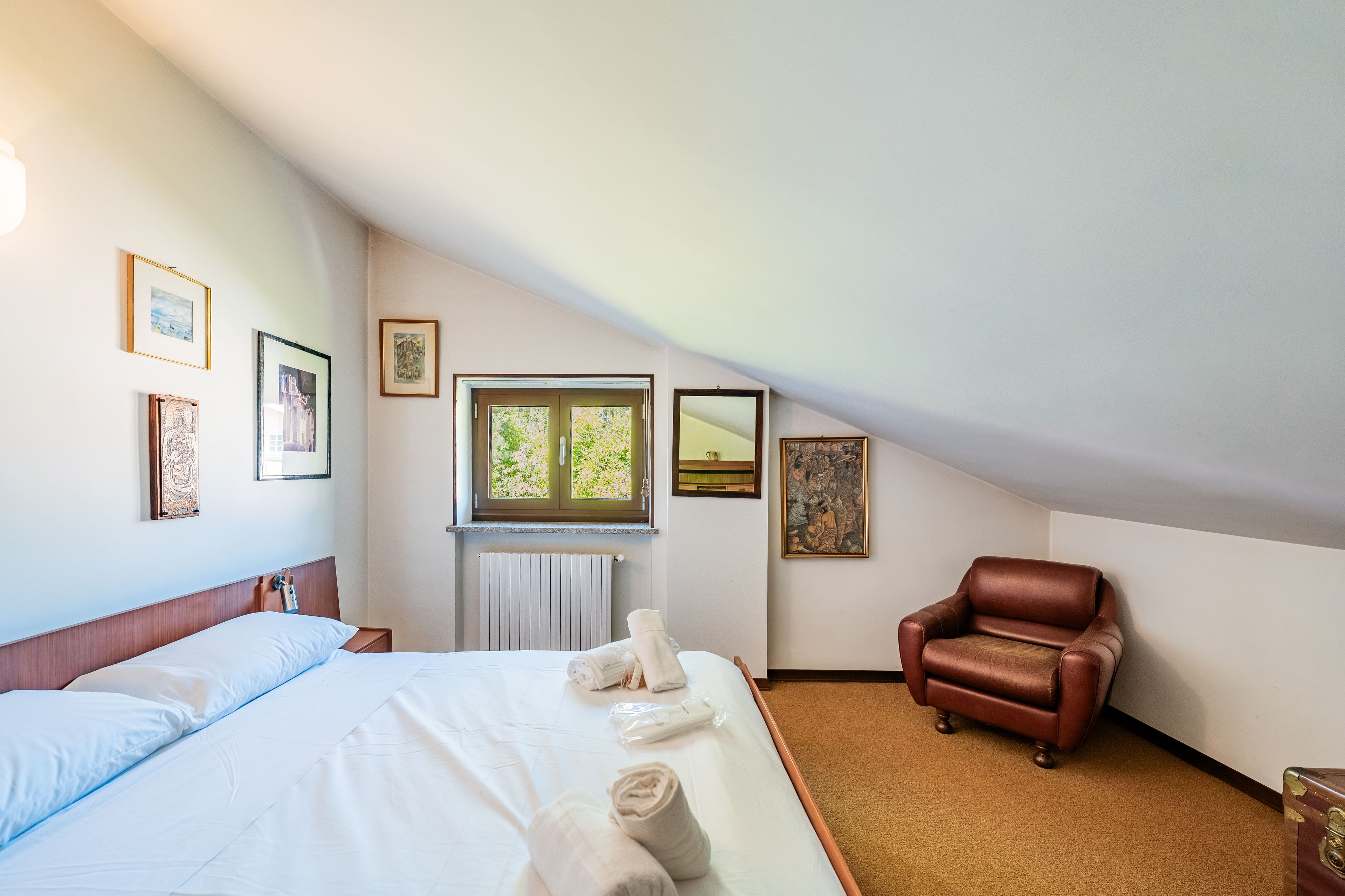 Une chambre d’hôtel avec un lit, une chaise et des œuvres d’art accrochées aux murs.