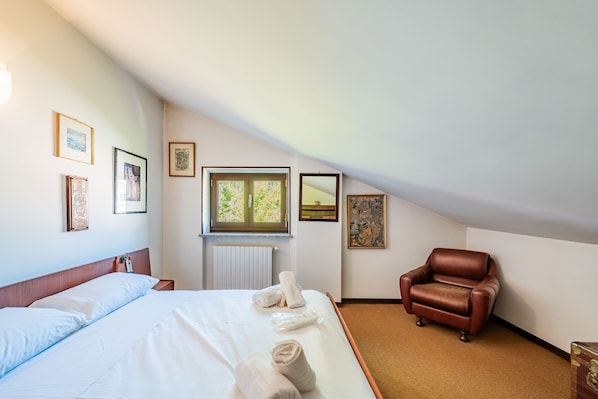 Habitació d'hotel amb llit, cadira i obra d'art a les parets.
