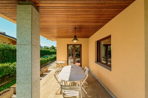 An outdoor patio with a wooden table and chairs, a hanging light fixture, and a view of a garden and neighboring buildings. - Il rifugio del viaggiatore antico (Santa Croce)