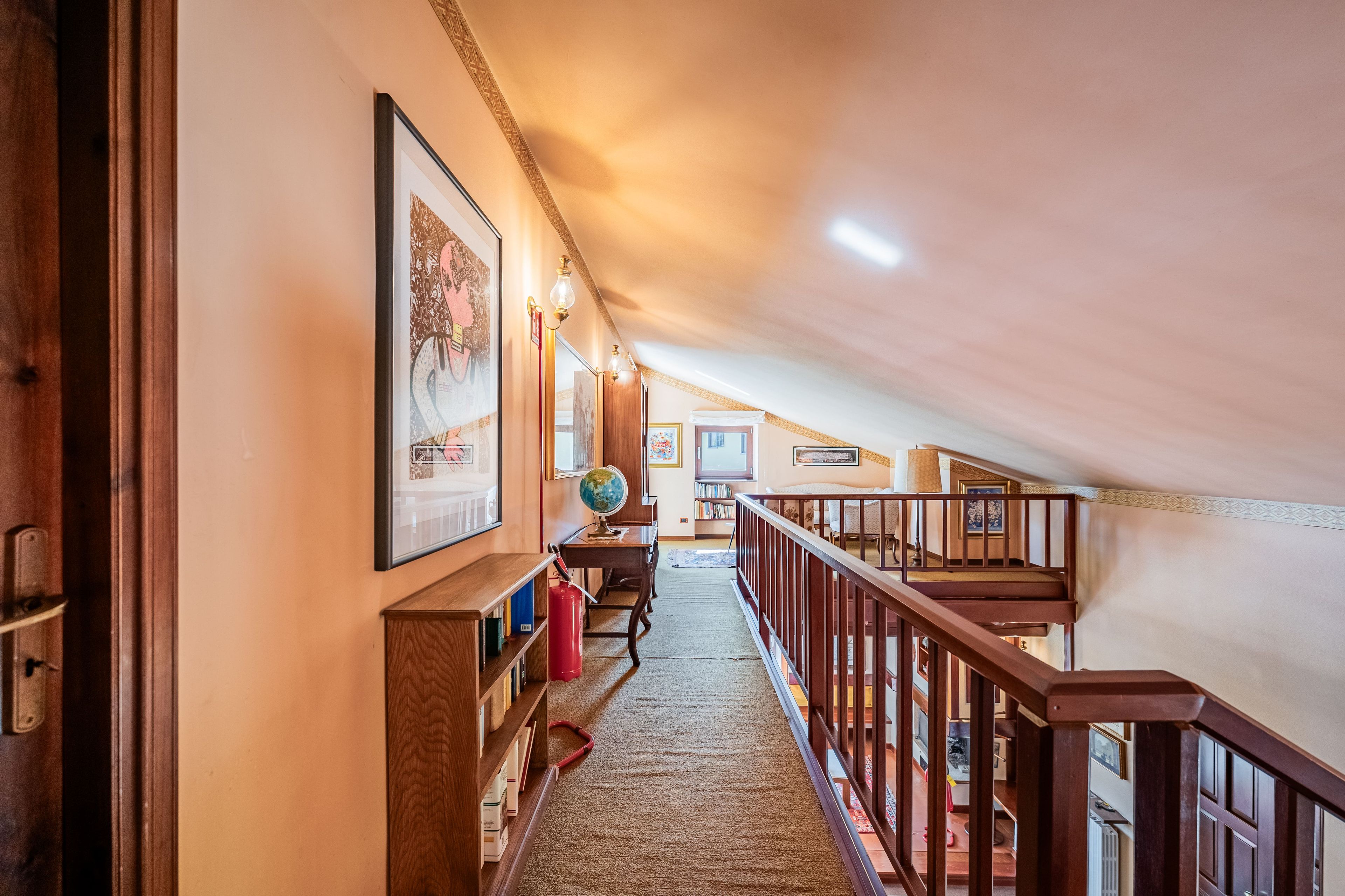 A hallway with a wooden staircase leading to an upper level.