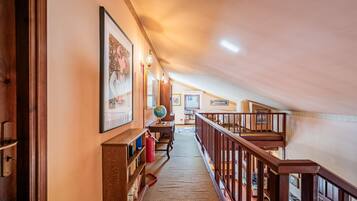A hallway with a wooden staircase leading to an upper level.