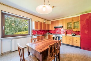 A kitchen with wooden cabinets, a red refrigerator, and a dining table with chairs.