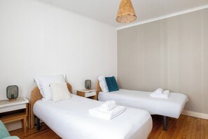 A hotel room with two single beds, a small bedside table with a lamp, and a woven light fixture. - Le Soleil d'Aléry - Annecy - 2 Bedrooms - Garage (Annecy)