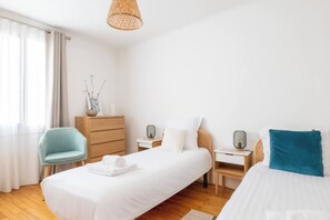 A hotel room with a bed, a chair, a dresser, a nightstand, and a lamp. - Le Soleil d'Aléry - Annecy - 2 Bedrooms - Garage (Annecy)