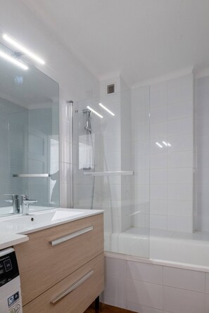 A modern bathroom with a white vanity, a large mirror, a shower, and a bathtub. - Le Soleil d'Aléry - Annecy - 2 Bedrooms - Garage (Annecy)