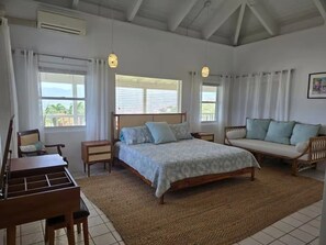 A bedroom with a bed, a sofa, a desk, and a chair. - Luxury 4BR Villa with Pool & Harbor Views (St. Thomas)