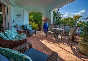 A covered patio with wicker furniture, a table, and a decorative turtle wall. - 4BR with pool very close to Neltjeberg Beach (St. Thomas)