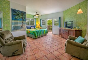 A bedroom with a bed, two armchairs, a TV, and a ceiling fan. - 4BR with pool very close to Neltjeberg Beach (St. Thomas)