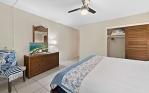 Ein Schlafzimmer mit Bett, Schminktisch, Spiegel, Deckenventilator und Kleiderschrank.