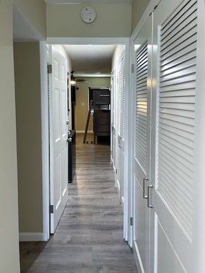 A narrow hallway with white doors and a wooden floor. - 1 BR condo on Sapphire Beach! Sleeps 6! (St. Thomas)