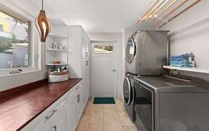 Eine kompakte Küche mit Holz Arbeitsplatte, Edelstahlgeräten und einer Hängeleuchte.