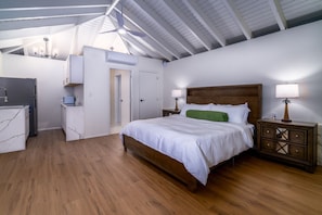 A bedroom with a wooden bed, white bedding, a nightstand with a lamp, and a ceiling fan. - Private 9BR Luxury Estate | Pool, Tennis, Views (St. Thomas)