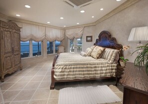 A bedroom with a large bed, a wooden wardrobe, and a view of the sea through large windows. - An Elite Traveller`s Top 10 Caribbean Villa (St. Croix)