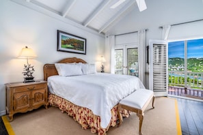 A bedroom with a large bed, wooden nightstand, and a view of a scenic landscape through the open door. - Bellevue Estate- 6BR New remodel w/Restoration Hardware & Tennis (St. Thomas)