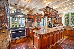 A spacious kitchen with a large island, built-in oven, stainless steel range hood, and copper cookware hanging above the island. - 2BR New remodel w/Restoration Hardware & Tennis (Charlotte Amalie East)