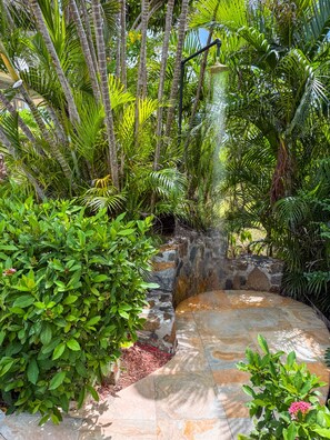 A circular stone patio surrounded by lush greenery and a small waterfall. - 2BR New remodel w/Restoration Hardware & Tennis (Charlotte Amalie East)
