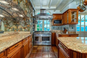 A kitchen with granite countertops, wooden cabinets, a stainless steel stove, and a large window with a view of the outdoors. - 2BR New remodel w/Restoration Hardware & Tennis (Charlotte Amalie East)