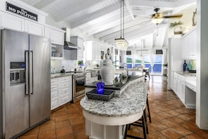 A modern kitchen with white cabinets, a stainless steel refrigerator, a granite countertop, and a view of the ocean. - 4BR Waterfront - 5 Minutes To Magen`s (St. Thomas)