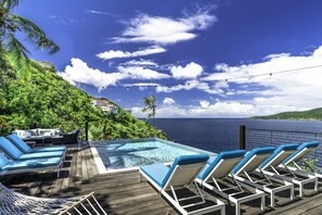 A poolside area with lounge chairs and a view of the ocean. - 4BR Waterfront - 5 Minutes To Magen`s (St. Thomas)