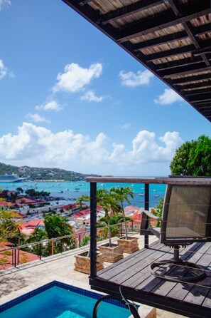 A pool area with a view of a coastal town and the sea. - Lissette Manor - 5BR historical estate next to The Pink Palm Hotel downtown! (St. Thomas)