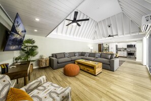 A spacious living area with a large sectional sofa, a wooden coffee table, and a ceiling fan. - Pineapple Village 3208 - beautiful, newly remodeled 2br condo- walk to Coki beach - sleeps 6! (St. Thomas)