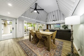 A spacious living area with a dining table, wicker chairs, a sofa, and a ceiling fan. - Pineapple Village 3208 - beautiful, newly remodeled 2br condo- walk to Coki beach - sleeps 6! (St. Thomas)