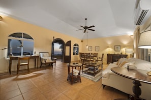 A spacious living room with a dining area, a large window, and a ceiling fan. - Classic West Indies Retreat with Timeless Soul (St. Thomas)