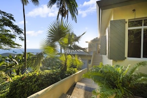 A tropical garden with palm trees and a view of the ocean. - Classic West Indies Retreat with Timeless Soul (St. Thomas)