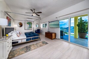 A bedroom with a bed, a ceiling fan, a TV, a dresser, and a view of the outdoors. - 4BR - centrally located & mins. from Magen`s Bay! (St. Thomas)