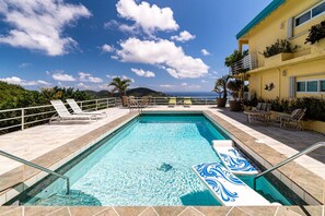 A swimming pool with lounge chairs and a view of the ocean. - 4BR - centrally located & mins. from Magen`s Bay! (St. Thomas)