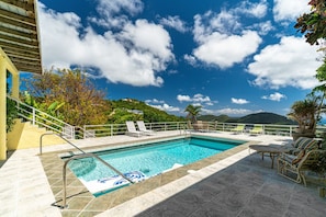 A swimming pool with a view of mountains, a covered patio area with lounge chairs, and a staircase leading to a building. - 4BR - centrally located & mins. from Magen`s Bay! (St. Thomas)