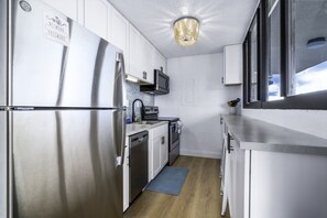 A compact kitchen with white cabinets, stainless steel appliances, a microwave, and a built-in oven. - Turquoise Dreams- 2br Condo- pool, restaurant and beach! (St. Thomas)