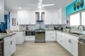 A modern kitchen with white cabinets, a stainless steel stove, and a marble backsplash. - Centrally located 3br with pool, incredible harbor views! (St. Thomas)