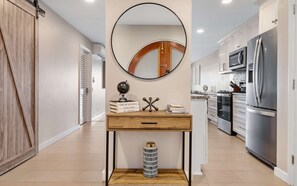 A modern kitchen with a central island, stainless steel appliances, and a wooden floor. - Beachside 2BR Condo in Cowpet Bay West - sleeps 6 (St. Thomas)