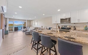 A modern kitchen with a marble countertop, stainless steel appliances, and a view of the sea. - Beachside 2BR Condo in Cowpet Bay West - sleeps 6 (St. Thomas)